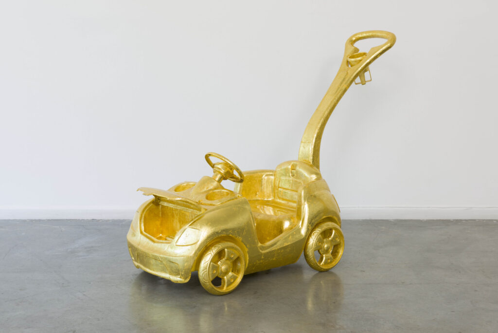 Image of a toddler's push car that has been covered with gold leaf.