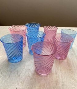 eight pink and blue blown glass cups with a spiral of lines on the surface