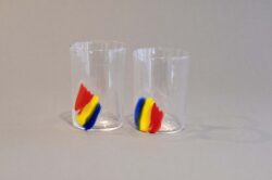Two clear blown glass cups with a red, yellow and blue striped patch.