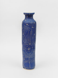 Skeletal II
2022 A tall slender blue wheel-thrown ceramic cylinder that has a smaller bottle neck and flared lip with a white interior. The surface is carved with lines representing pathways of energy movement within the skeletal system.
