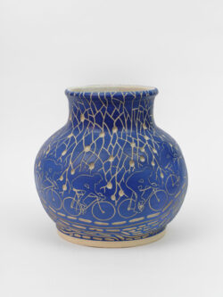 Lymphatic III
2022 A large blue wheel-thrown ceramic vessel that has a wide round shoulder and comes to a smaller opening at the top with a white interior. The surface is carved with images of a bicyclist riding around the center of the pot. Surrounding the cyclist are patterns of lymphatic vessels.