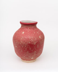 Neural III
2022 A large red wheel-thrown ceramic vessel that has a wide round shoulder and comes to a smaller opening at the top with a white interior. The surface is carved with images of a face and the tongue licking a ball on a string, anatomical drawings of the clitoris, surrounded by abstract lines and pattern.