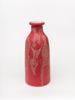 Muscular I 2022 A tall slender red wheel-thrown ceramic cylinder that has a smaller bottle neck and flared lip with a white interior. The surface is carved with different lines of the muscular system of the human body.