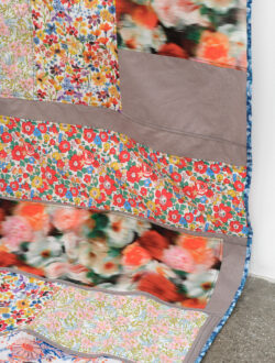 Air 2022 A detail of the Air quilt showing where the quilt drapes onto the floor. There are floral patterns on the fabrics.