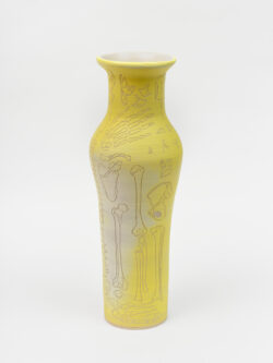 Skeletal I
2022 A tall, yellow wheel-thrown ceramic vessel that has a wider round shoulder and comes to a smaller opening at the top, much like a bottle, with a white interior. The surface is carved with diagrams of the skeletal system.