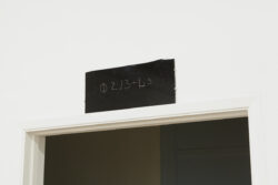 Exit Blessing
2015 Image of a black piece of glass with unknown writing etched into the surface. It is hanging above a door frame.