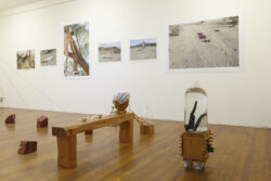 Installation View
2015 Installation view of the exhibition Oh Be Gentle. It shows several photographs on the wall in the background, with a bench holding a vessel on it and a cart with a large clear vessel on top of the cart.
