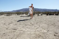 Wettest One Here
2015 Photograph of a naked white person standing in a desert with a shawl of empty water jugs hanging over their body.